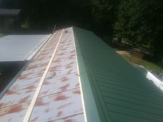 Old rusted panels beside newly installed green metal roofing — Wind Damage Roof Repair by Roofing Brothers in Croton Falls