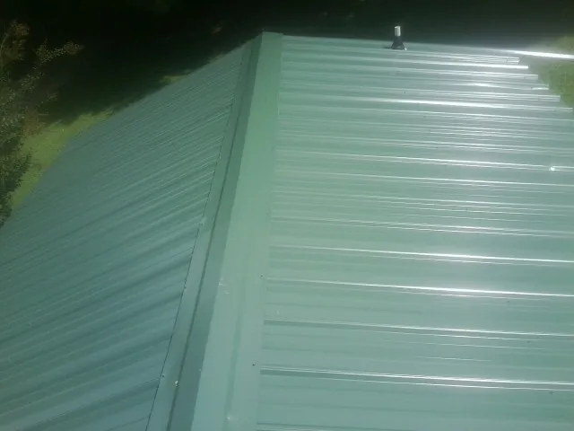 New green metal panels meeting at the ridge of a roof — Flat Roof Repair work by our crew in Croton Falls