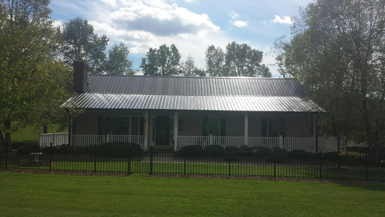 Gray metal roof on a brick ranch with a full width front porch — Gutter Guard Installation work by our crew in Croton Falls