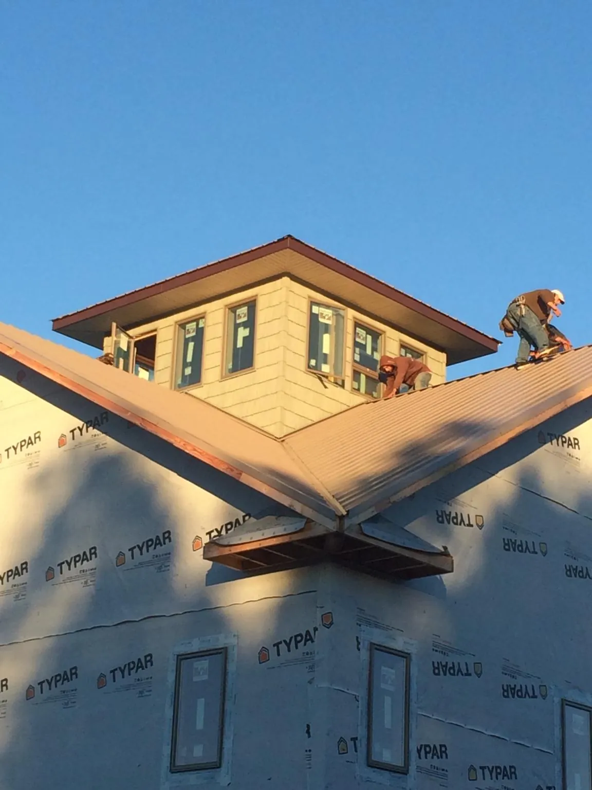 Roofers working around a rooftop cupola on a new metal roof at sunset — Roof Waterproofing in Croton Falls by Roofing Brothers